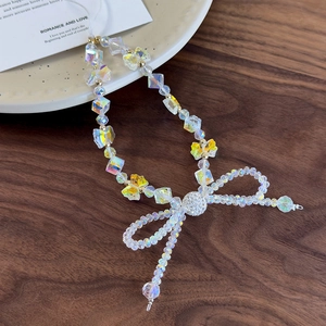 Detailed view of beaded phone charm with iridescent butterfly bow and crystal beads