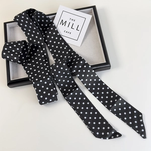 Foulard en soie à pois noir et blanc pour femmes présenté sur un plateau à bijoux