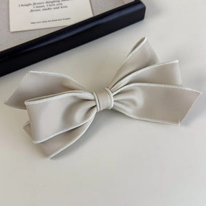 Détail d'une pince à cheveux nœud en cuir souple beige avec coutures blanches élégantes