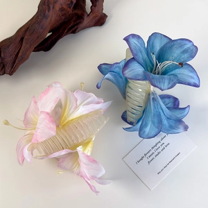 Detailansicht der Lilienblüten-Haarklammern in Rosa und Blau auf einem cleanen Hintergrund