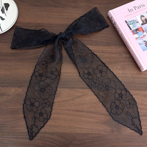 Detail of black lace hair ribbon with floral embroidery and bow knot on wood background