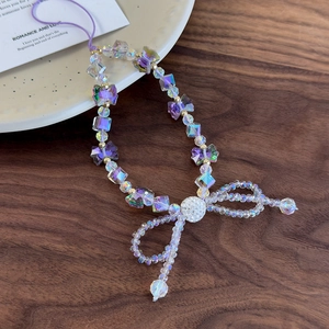 Detailed macro view of pearlescent crystal beads and purple bow pendant phone strap charm