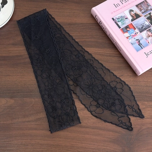 Detail of black lace ribbon with floral embroidery and white Love text on wood