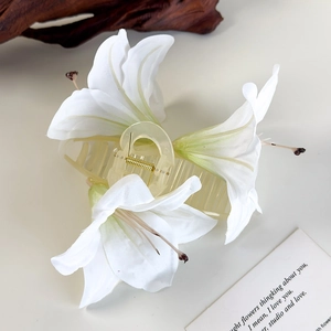 Detail der weißen Lilien-Haarklammer mit realistischen Stoffblüten und goldener Feder
