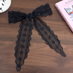 Detail of black lace bow hair tie featuring intricate floral embroidery and scalloped edges