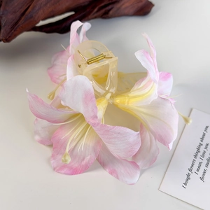 Detail der eleganten Lilien-Haarklammer mit rosa Farbverlauf und goldener Metallfeder