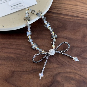 Detailed view of handmade crystal beaded phone charm with a large bow and golden accents