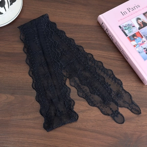Close-up of black floral lace headband with scalloped edges on a wooden surface