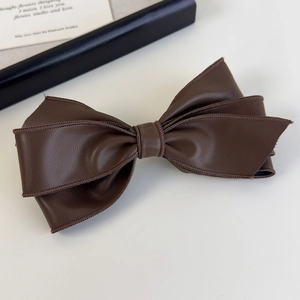 Détail d'une pince à cheveux nœud en cuir PU marron avec couture fine et texture douce