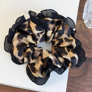 Retro leopard print scrunchie with black chiffon lace trim on elegant wood background