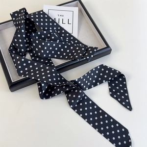 Foulard étroit à pois noirs et blancs pour cheveux ou sacs sur un plateau minimaliste