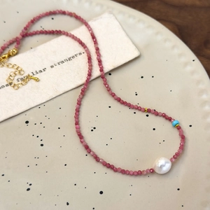 French romantic choker with pink stones, baroque pearl, and gold accents on a tray
