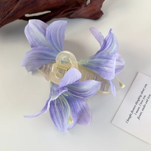 Detailansicht der violetten Lilien-Haarklammer mit Seidenblüten und goldener Feder