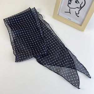 Dettaglio di sciarpa in seta nera a pois con eleganti bordi ondulati per donna