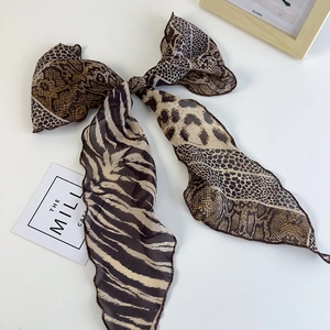 Dettaglio di un grande fiocco in chiffon con motivi leopardati e zebrati su sfondo bianco