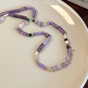 Handmade necklace with purple amethyst stones and white pearls on a ceramic plate