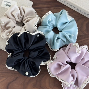 Detail view of satin hair scrunchies with white lace edges and delicate pearl beads