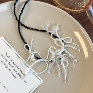 Detail of black and white beaded necklace with handmade woven crystal bow accents