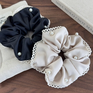 Close-up of elegant satin hair scrunchies with white lace edges and pearl details
