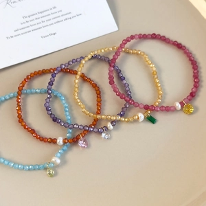 Détail de cinq bracelets en perles colorées avec breloques de perles sur plateau