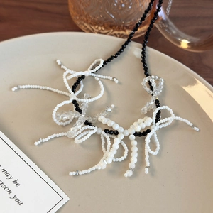 Detailed view of black and white beaded bow necklace with clear crystal accents