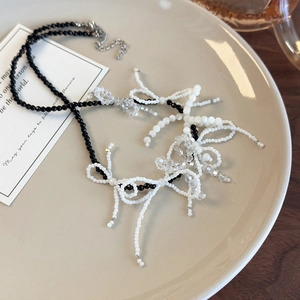 Detail of handcrafted black and white beaded necklace with delicate woven bow accents