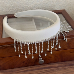 Close-up of white satin padded headband with shimmering rhinestone fringe tassels