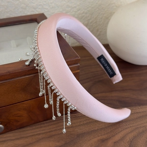 Detailed macro view of pink velvet headband with shimmering rhinestone fringe and handmade label