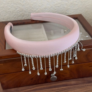 Detail of pink satin headband with crystal tassels on a vintage wooden jewelry box