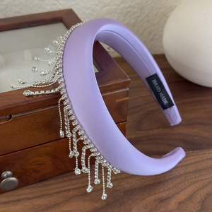 Detail view of light purple satin padded headband with dangling rhinestone fringe accents