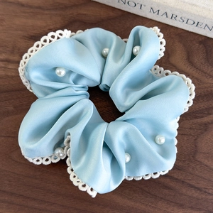 Close-up of light blue satin scrunchie with white lace trim and faux pearls details