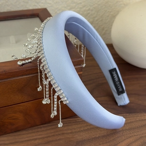 Detail of light blue padded headband with silver rhinestone tassels and handmade label
