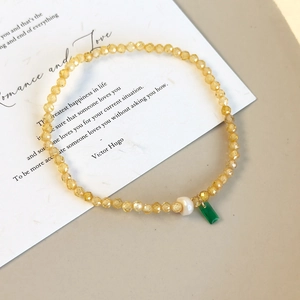 Détail d'un bracelet en perles de cristal jaune avec pendentif rectangulaire vert et breloque