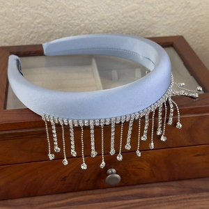 Detail of light blue satin headband with shimmering rhinestone tassels on a jewelry box