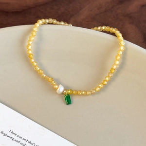 Vue détaillée des perles jaunes facettées avec perle baroque blanche et pendentif vert