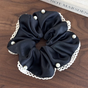 Detail of elegant black satin scrunchie with white lace edges and decorative pearls