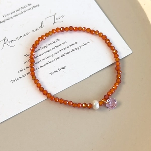 Vue détaillée du bracelet perlé avec cristaux orange, perle blanche et pendentif rose