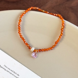Vue détaillée du bracelet en perles orange avec perle et pendentif en cristal rose