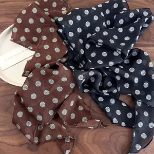 Elegant brown and black polka dot chiffon scarf headband displayed on a wooden surface