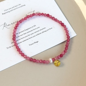Détail du bracelet en perles roses facettées avec perle et pendentif gemme jaune