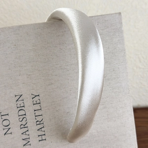Macro shot of padded champagne gold satin headband with elegant smooth silk texture