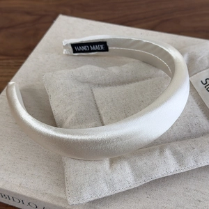 Detailed view of handmade beige satin padded headband with silk luster and interior label