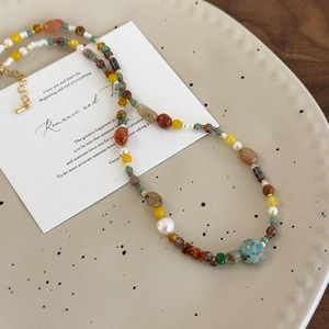 Collier artisanal perles et pierres naturelles sur une assiette en céramique