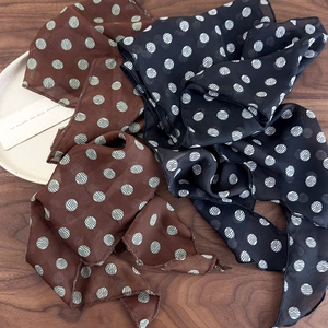 Brown and black polka dot silk scarf for women displayed on a rustic wooden table