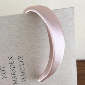 Detail of pink satin padded headband with shimmering pearlescent finish on a book