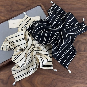 Nahaufnahme von minimalistischen Seidenschals mit Streifen und eleganten Perlenanhängern