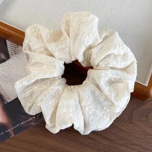 Detail of cream oversized scrunchie with floral embroidery and textured fabric