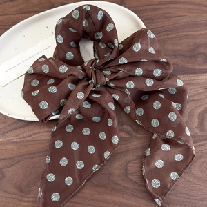 Close-up of brown chiffon hair tie with light blue polka dots and a bow detail