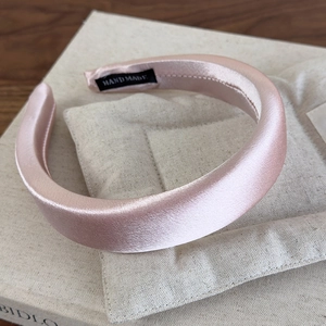 Detail of light pink satin padded headband with a hand made label on interior