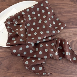 Close-up of brown polka dot silk scarf with sheer texture and wavy edge stitching